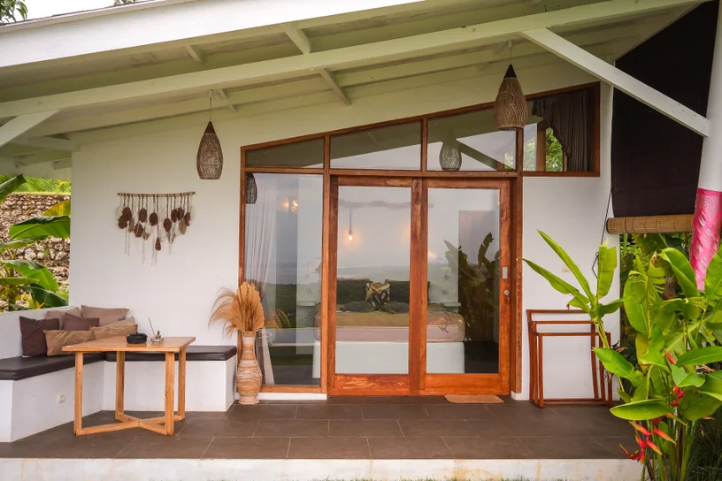 Villa bedroom with king bed and teak ceiling opening onto the pool